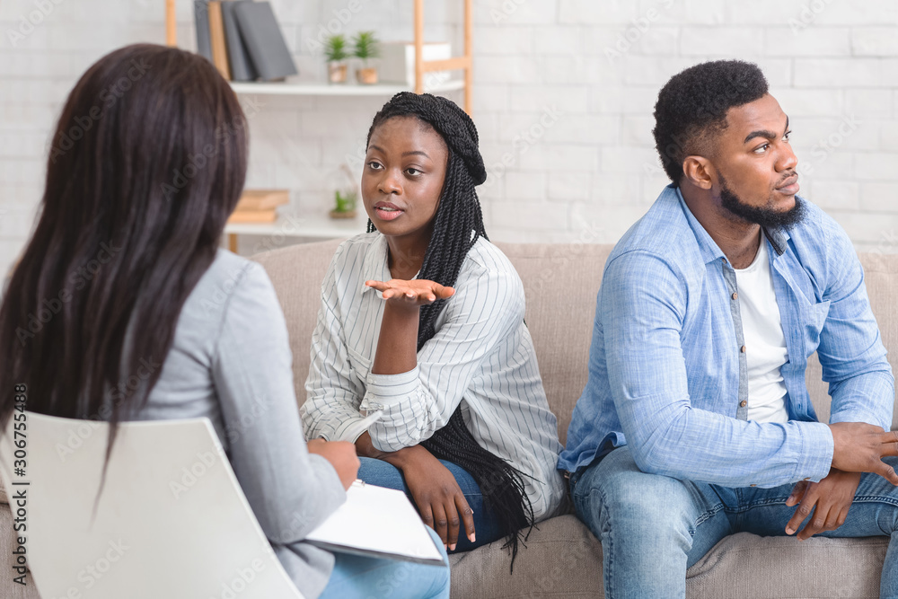 Wife Sitting Next To Her Displeased Husband And Talking To Counselor Wife Sitting Next To Her Displeased Husband And Talking To Counselor