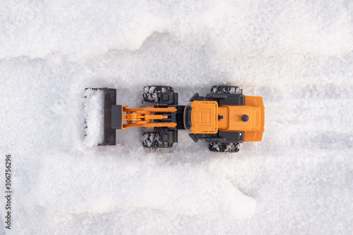 A toy tractor cleaning street from a snow concept.
