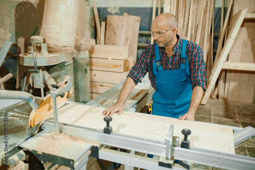 Carpenter cuts wooden board on circular saw