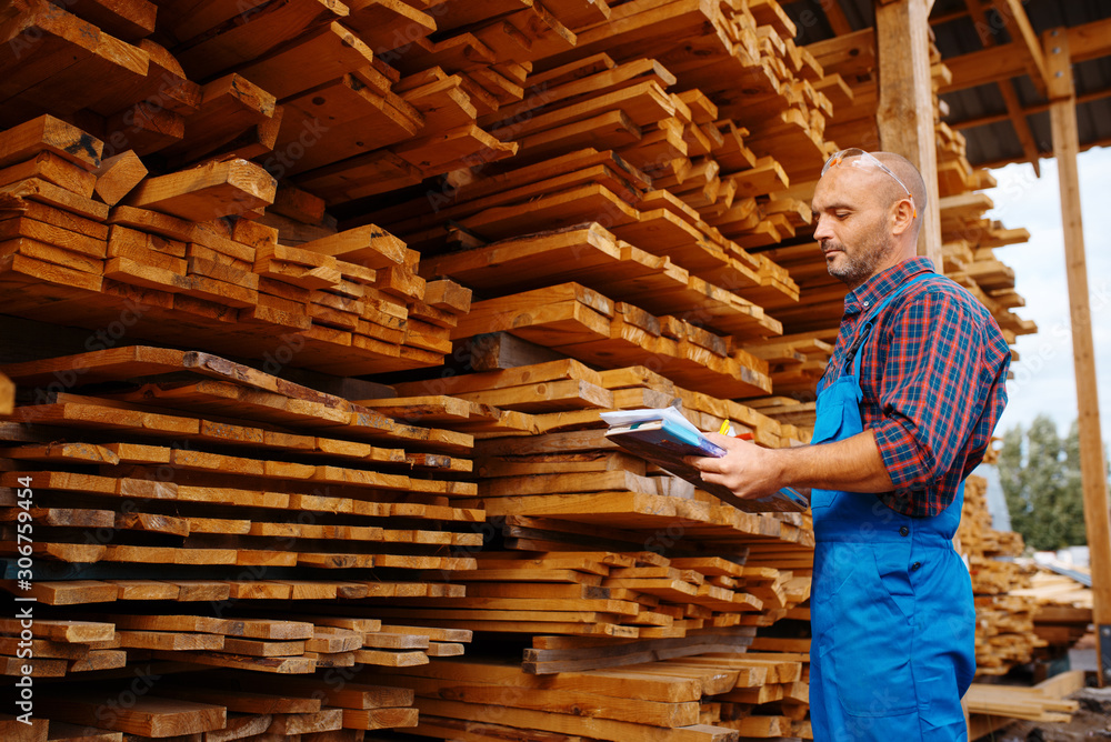 Carpenter in uniform check boards on sawmill