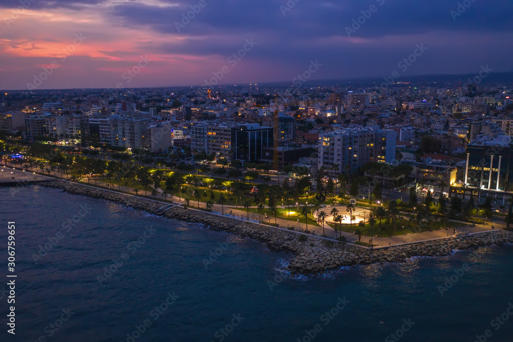 Aerial view of Limassol promenade or embankment with alley and buildings in Cyprus at night. Drone photo of mediterranean sea resort from above.