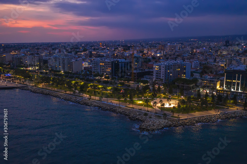 Aerial view of Limassol promenade or embankment with alley and buildings in Cyprus at night. Drone photo of mediterranean sea resort from above.