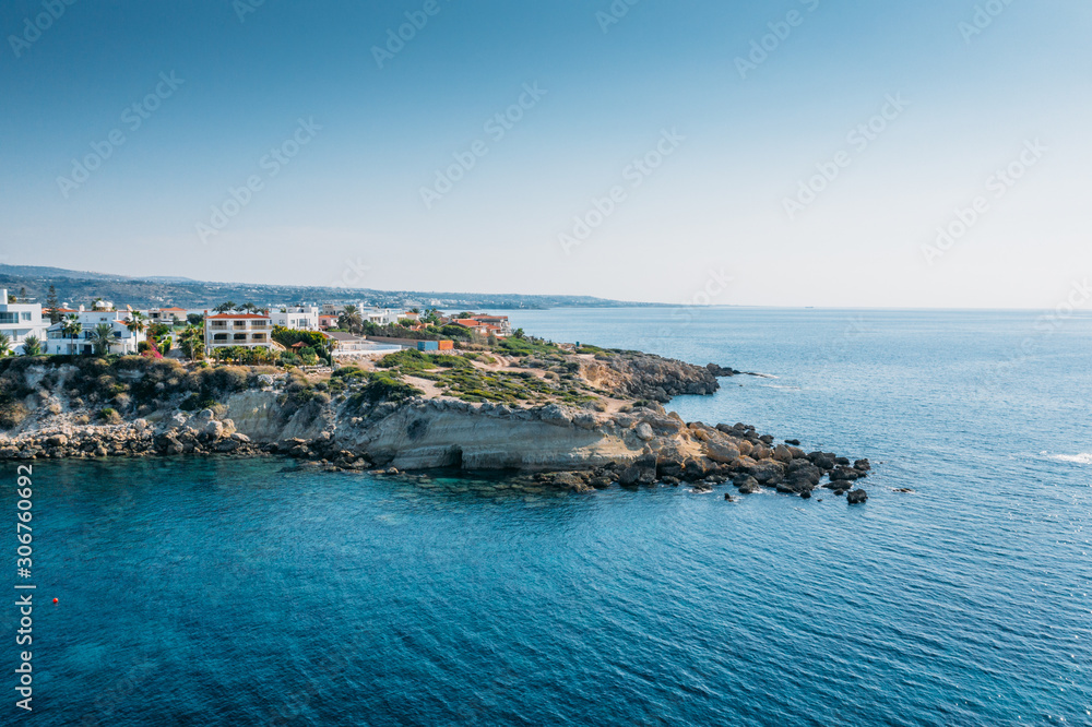Aerial view of beautiful nature cliff with villas or houses near Coral Bay beach in Paphos, Cyprus. Drone photo of mediterranean seascape background.