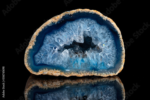 Geode with crystals of blue color. Quartz geode with transparent crystals on a black mirror background..