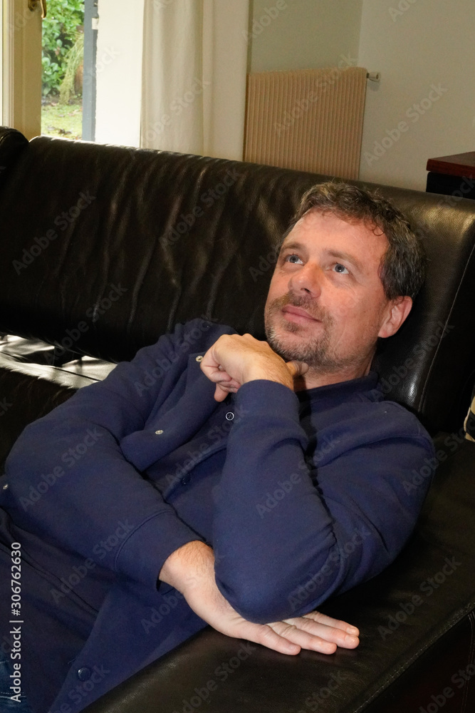 pensive relaxed man resting on a couch at home house look up pensive relaxed man resting on a couch at home house look up