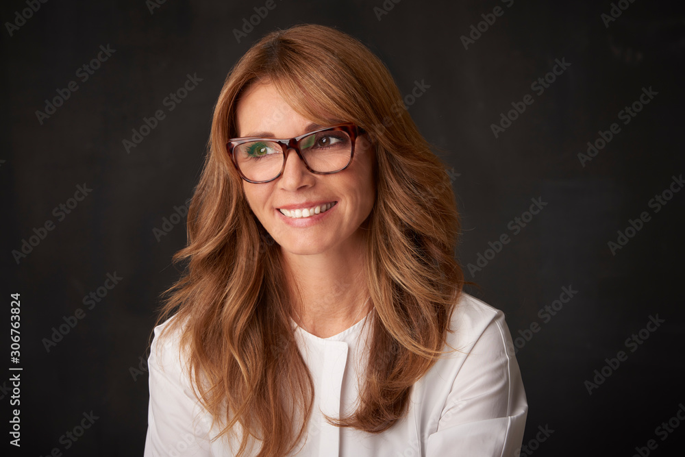 Fototapeta premium Close-up portrait of beautiful happy mature woman posing against at grey background and looking away.