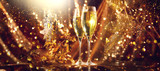 Holiday Champagne Flute over Golden glowing background. Christmas and New Year celebration. Two Flutes with Sparkling Wine over Holiday Bokeh Blinking Background. Table setting, decoration
