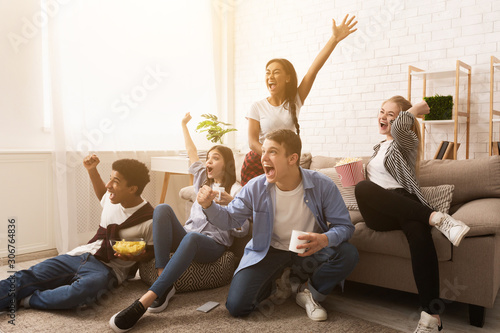 Emotional teenagers cheering for favourite team, watching match