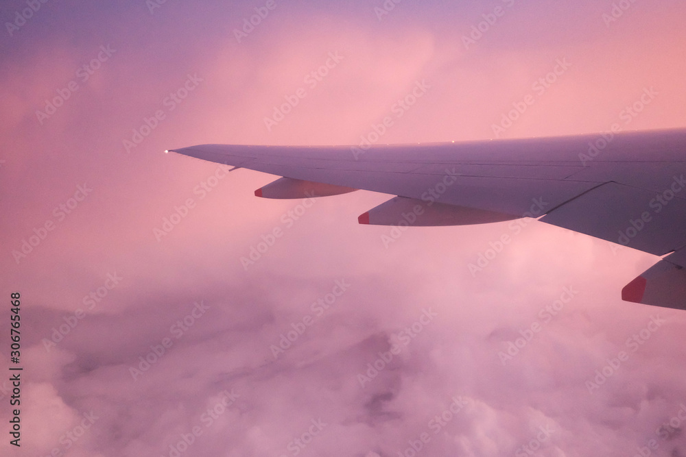 Fototapeta premium Colorful fluffy clouds with dawn sky and blur airplane wing, a view from a plane window