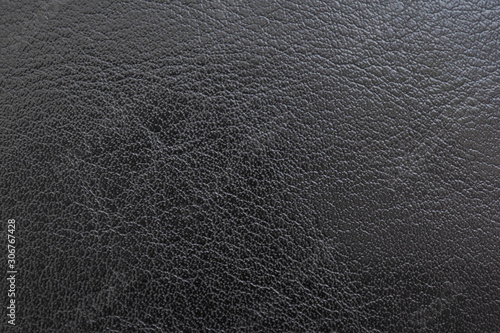 Black polished leather surface. Dark background or wallpaper. Natural material. Reduced contrast. View from above. Macro