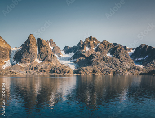 Arctic landscape in summer with high mountains and icebergs floating on the sea in Ofjords, Scoresby Sound, East Greenland photo