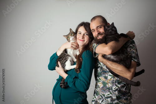 Man and woman holding a cat. Cat lovers. Two people hug two cats. 