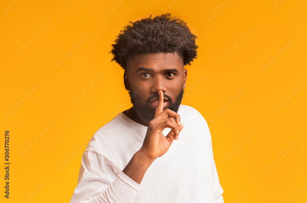 Handsome silent black man making hush gesture