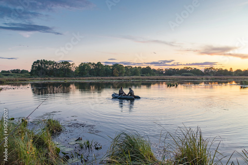 Hunters in a boat swim in a pond in search of wild ducks