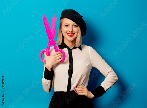 beautiful french woman in beret big scissors on blue background