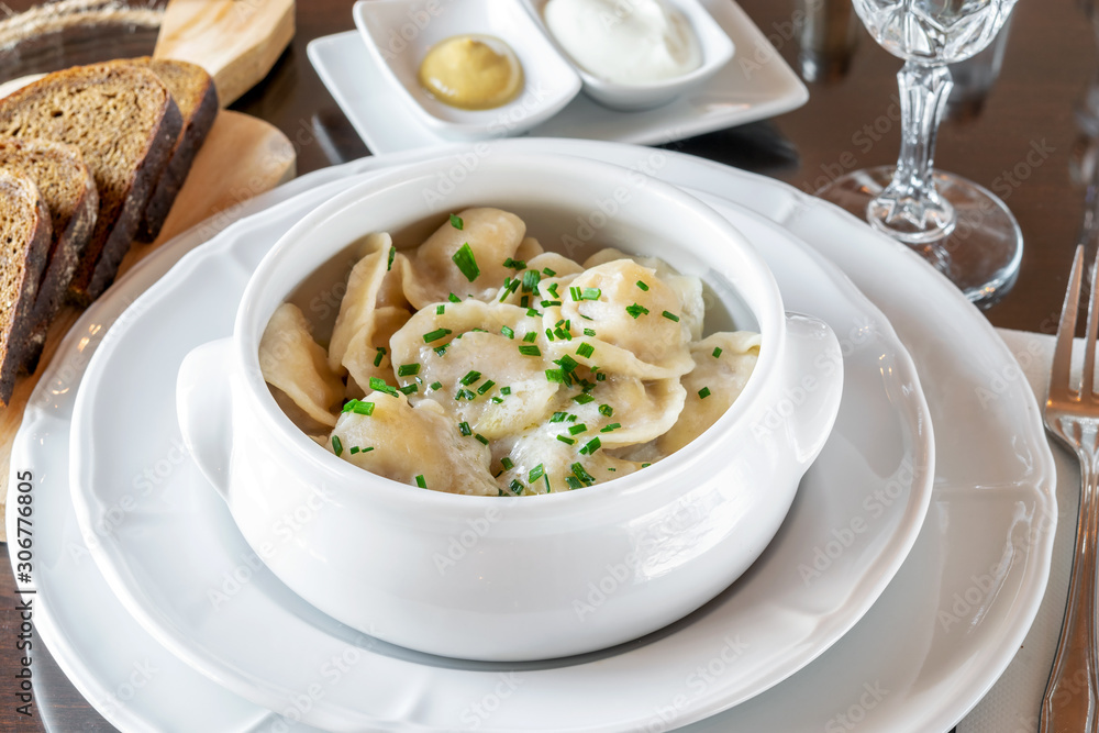 Boiled dumplings with green onion and butter in the white ceramic bowl, served on the table of restaurant. Boiled dumplings with green onion and butter in the white ceramic bowl, served on the table of restaurant.