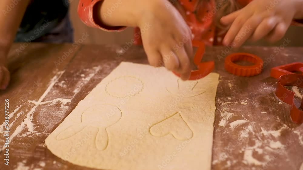 Girl on the kitchen table preparing cookies from thinly rolled dough with a variety of special molds for cutting out the dough. Girl on the kitchen table preparing cookies from thinly rolled dough with a variety of special molds for cutting out the dough.