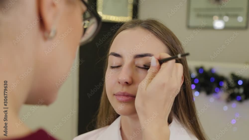 Professional eye makeup. Stylist makeup artist applies makeup to a young woman with a special brush in a beauty salon. Professional eye makeup. Stylist makeup artist applies makeup to a young woman with a special brush in a beauty salon.