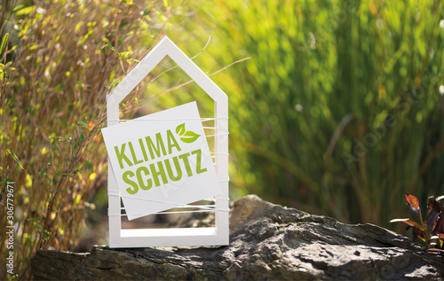 Weißes Haus vor natürlichen Hintergrund mit Schild Klimaschutz photo