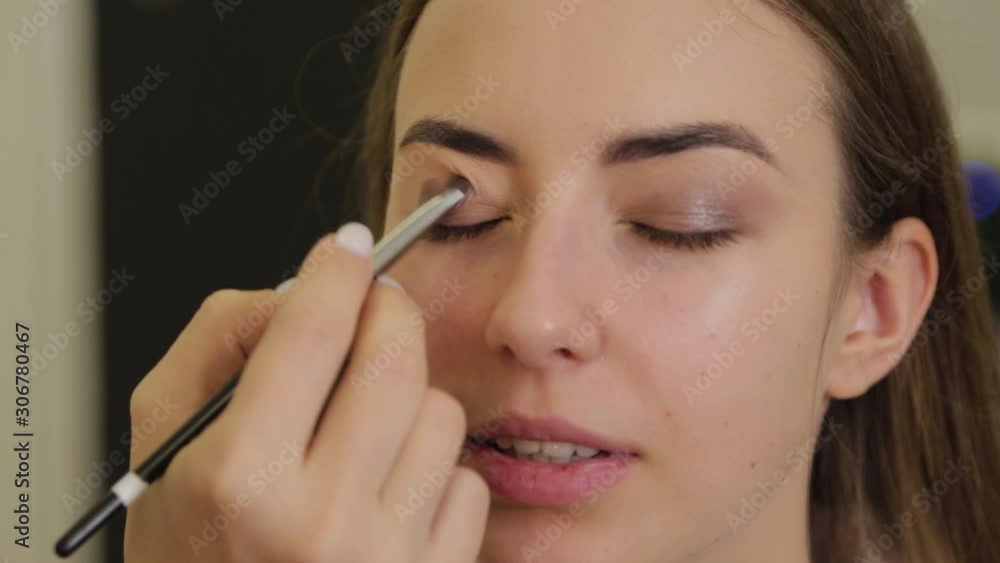 Professional eye makeup. Stylist makeup artist applies makeup to a young woman with a special brush in a beauty salon. Professional eye makeup. Stylist makeup artist applies makeup to a young woman with a special brush in a beauty salon.