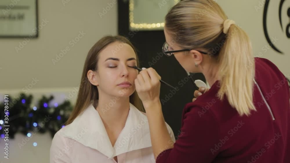 Professional eye makeup. Stylist makeup artist applies makeup to a young woman with a special brush in a beauty salon. Professional eye makeup. Stylist makeup artist applies makeup to a young woman with a special brush in a beauty salon.