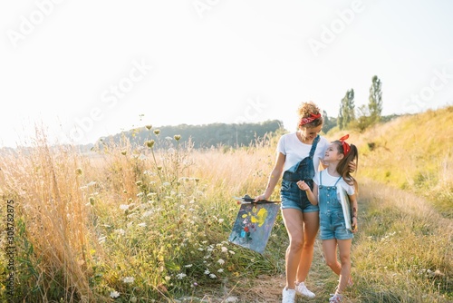 Young mother and her daughter have fun  mother s Day. smiling mother with beautiful daughter draws nature