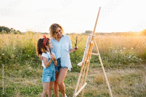Young mother and her daughter have fun, mother's Day. smiling mother with beautiful daughter draws nature