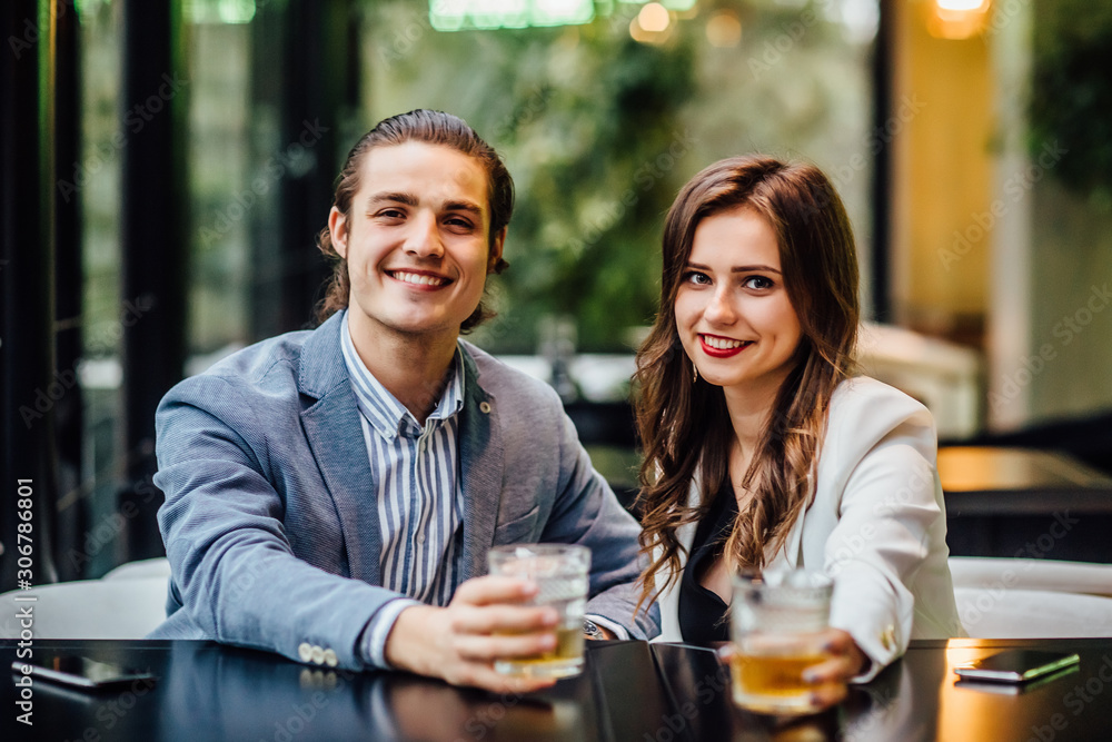 Lovely concept, pretty young and cheerful couple with drinks on hands spend time at modern restaurant. Lovely concept, pretty young and cheerful couple with drinks on hands spend time at modern restaurant.