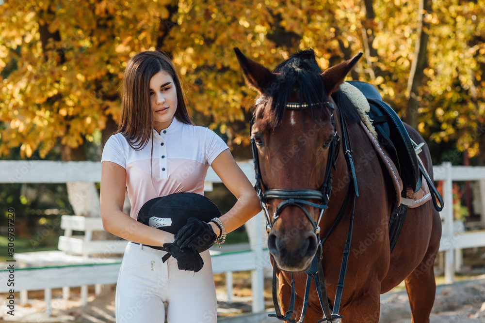Obraz premium Apretty jockey girl holding helmet before competition. The girl loves animals and horseback riding.