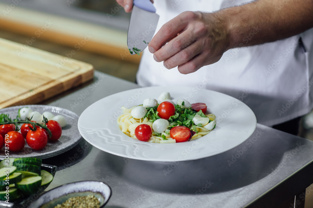 Man hand cutting eggs on chopping wood board for spaghetti carbonara, with sharp knife and cooking vegetables salad in kitchen. Man hand cutting eggs on chopping wood board for spaghetti carbonara, with sharp knife and cooking vegetables salad in kitchen.