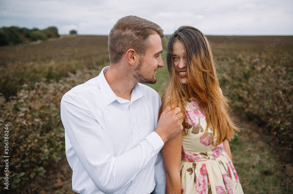 Fototapeta premium A girl and a guy are walking in the nature. Portrait of a couple, a love story.Happy smiling, loveing couple together outstretched at beautiful nature. Lovestory
