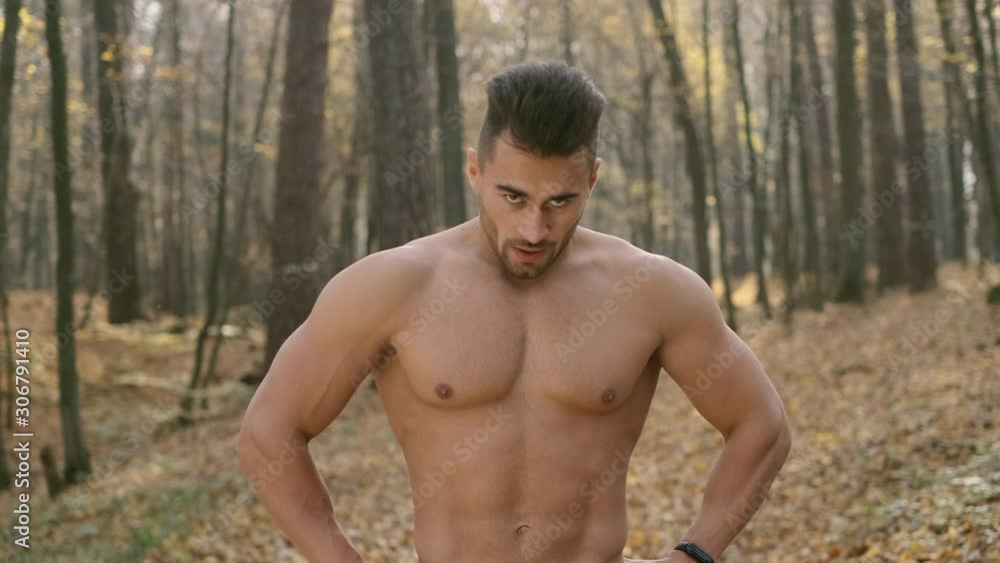 Young Athletic Guy With Naked Torso Stands In The Woods And Does Breathing Exercises. Young Athletic Guy With Naked Torso Stands In The Woods And Does Breathing Exercises.