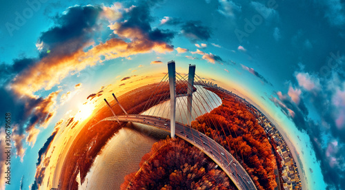 Beautiful panoramic aerial drone view to cable-stayed Siekierkowski Bridge over the Vistula river and Warsaw City skyscrapers, Poland in gold red autumn colors in November evening at sunset photo