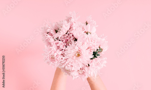Beautiful flowers composition. Women's hand hold bouquet of pink light flowers on pastel pink background. Valentines Day, Mother's day. Flat lay, top view, copy space