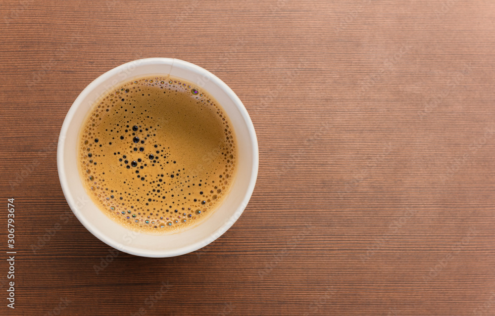 Top view of paper cup of black coffee on brown wooden table Top view of paper cup of black coffee on brown wooden table