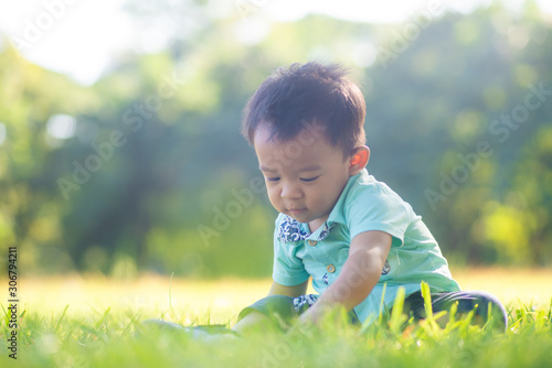 Adorable smart baby boy playing in city green park