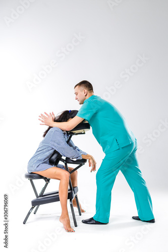 Theme massage and office. Male therapist with blue suit doing back and neck massage for young woman worker, business woman in shirt on massage chair shiatsu