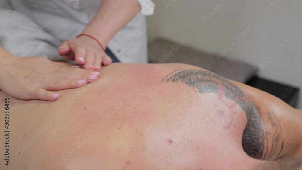 Professional woman masseur doing massage on the back of a man. Massage at the beauty salon. Professional woman masseur doing massage on the back of a man. Massage at the beauty salon.
