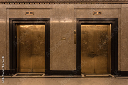 Two gold door elevators in a marble lobby