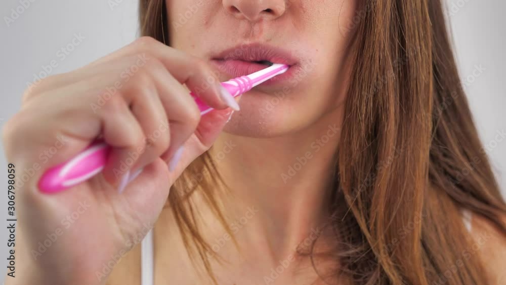 Close up portrait a young woman which brushes her teeth after waking up on a white background after . Hygiene concept. 4k Close up portrait a young woman which brushes her teeth after waking up on a white background after . Hygiene concept. 4k