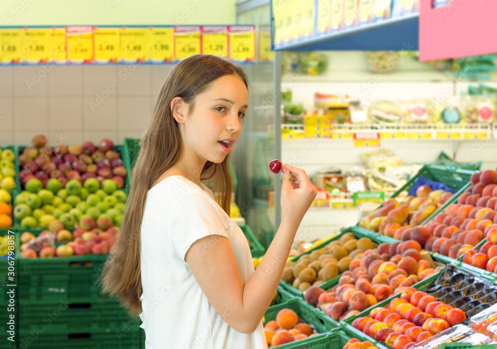 Teen girl shopping in the supermarket at the vegetable section. Choosing daily product