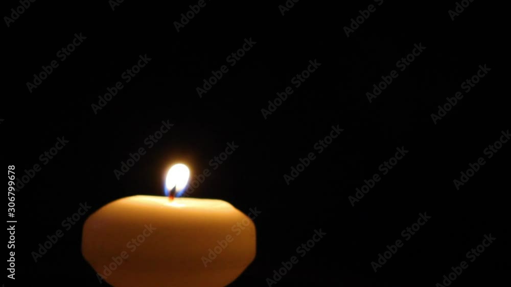 Candle lights flame on its own and extinguishes on black background.
