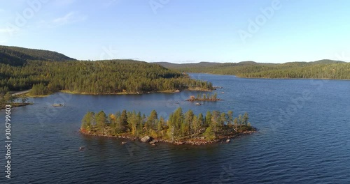 Lake Inarijarvi in Lapland, Aerial, tracking, drone shot, overlooking islands, hills, foliage forest and autumn color nature, in Inari, on a sunny, fall day, in Lappland, North Finland photo