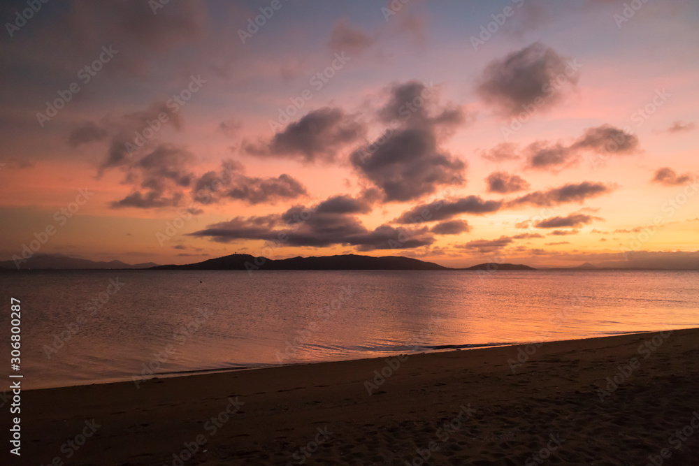 Colourful sunset at the beach with mountains in the background