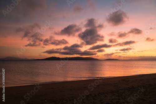 Colourful sunset at the beach with mountains in the background