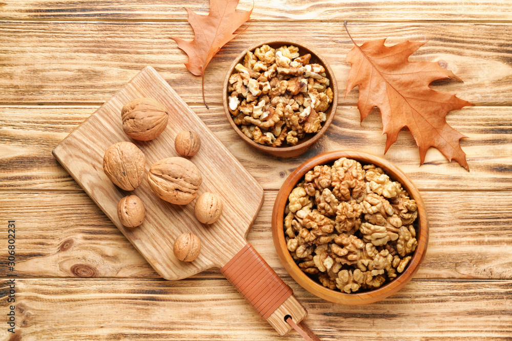 Tasty walnuts with autumn leaves on wooden table