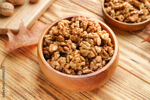 Bowl with tasty walnuts on wooden table