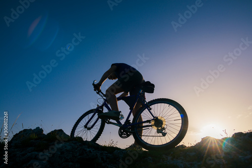 Silhouette of a mountain biker riding his mountain sportbike on top of a cliff ( hill).