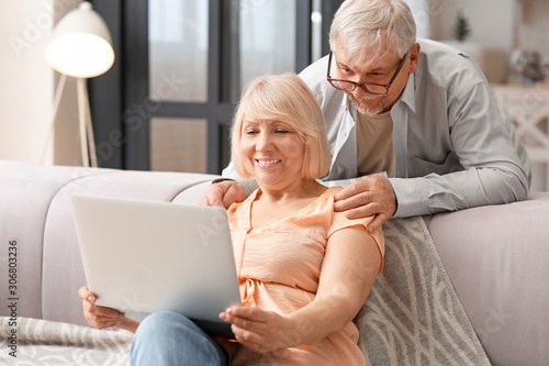 Mature couple with laptop resting at home