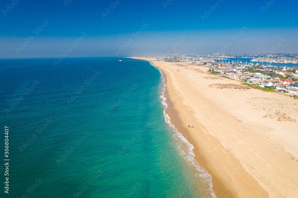 Aerial drone shot over Orange County, California with beach and sand below on a sunny Summer blue sky day.